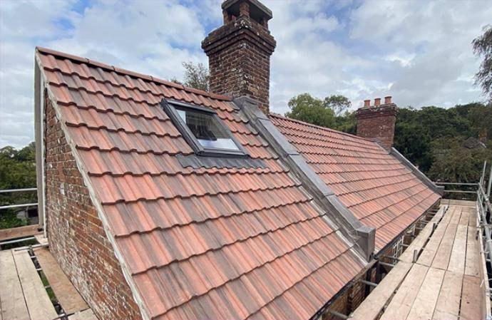 Interlocking tile re-roof with bespoke leadwork, a Velux window and brick chimneys